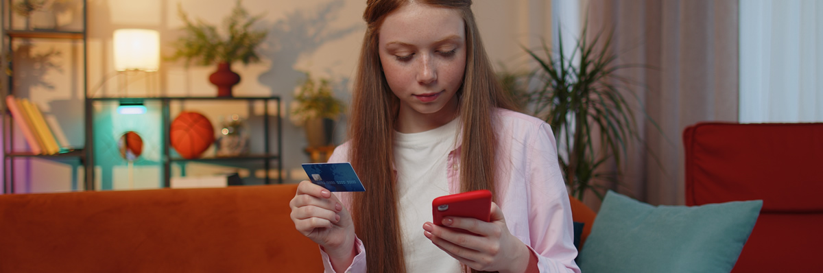 Junge Frau kauft etwas mit dem Handy und mit der Kreditkarte