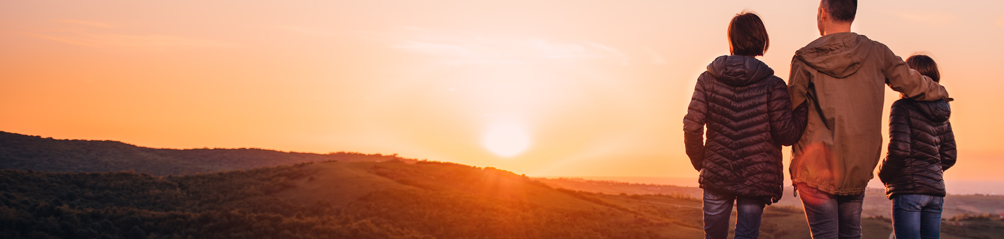 Kleines Mädchen, das bei Sonnenuntergang auf der Wiese mit Windmühle in den Händen läuft.